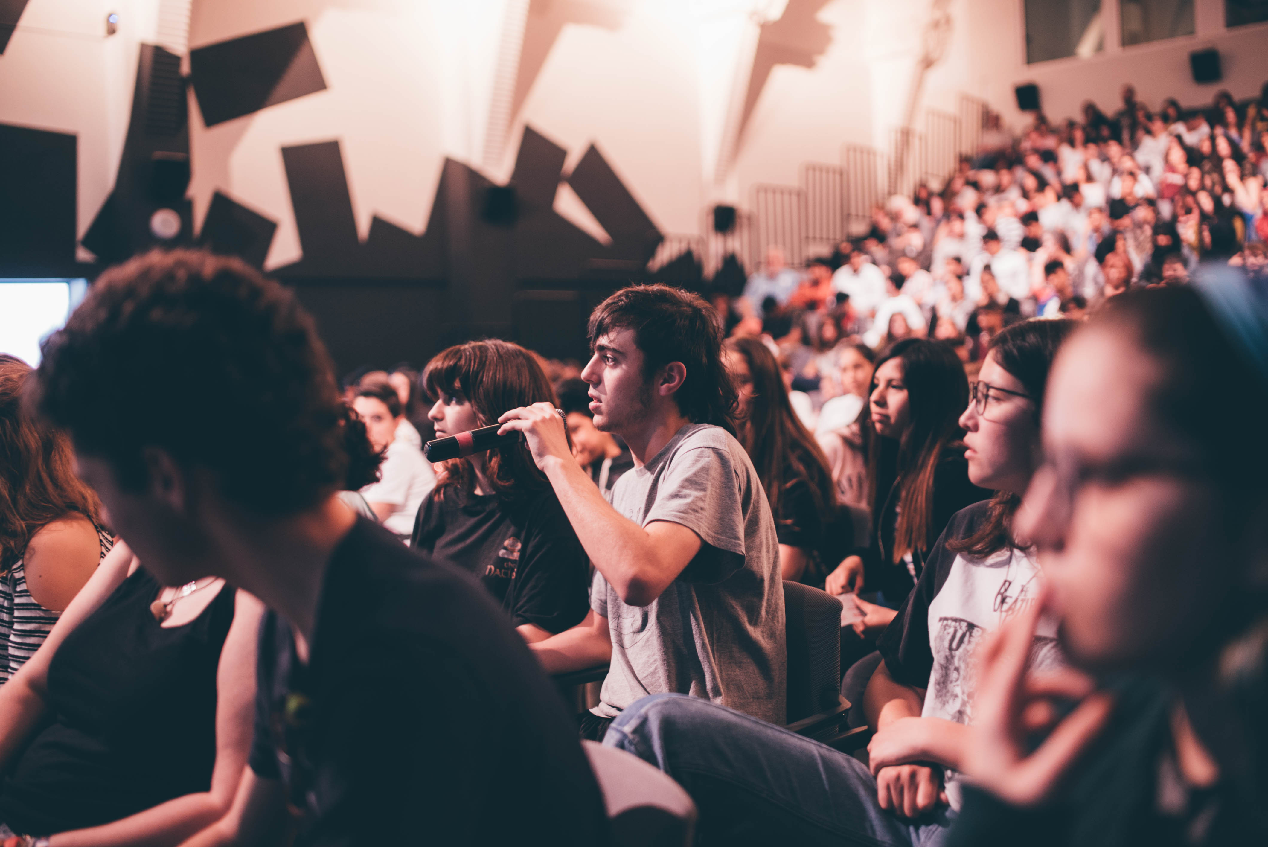 Público adolescente haciendo preguntas en un coloquio de cine.